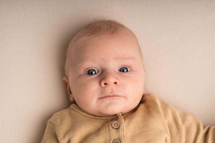 Een baby die op een doek ligt en naar de camera kijkt.