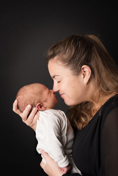 Pasgeboren baby met mama voor zwarte achtergrond. Newbornshoot in fotostudio Beuningen.