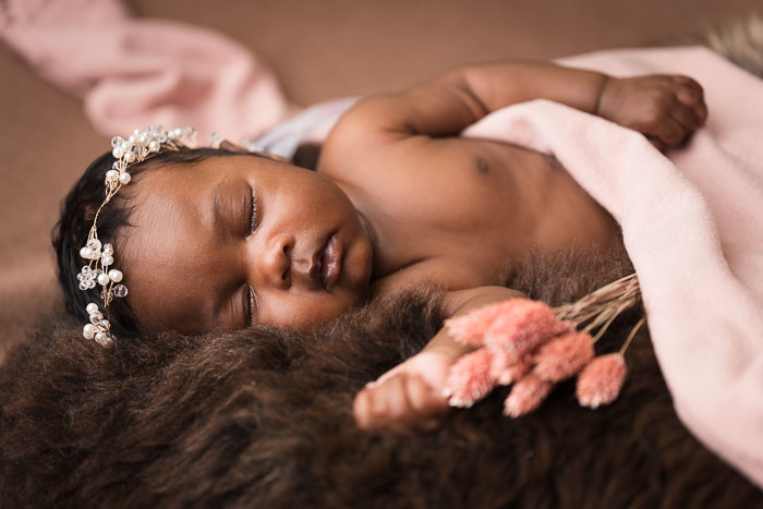 Baby meisje op bruin vacht met roze doek