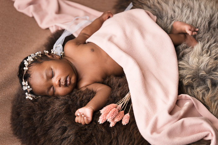Baby meisje op bruin vacht met roze doek, newbornshoot