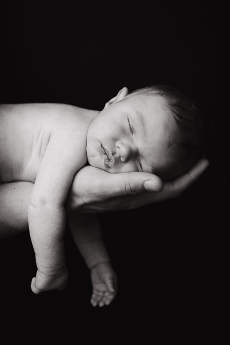Newbornshoot, baby liggend op hand zwart-wit