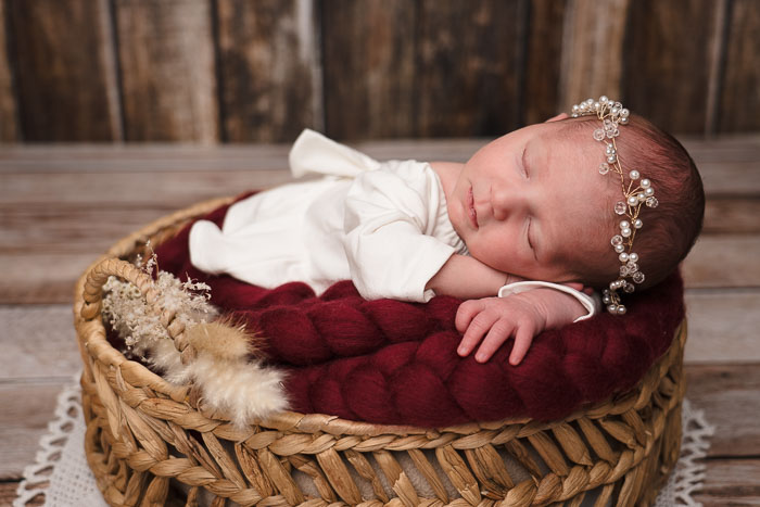 Newborn baby in mandje met wit jurkje