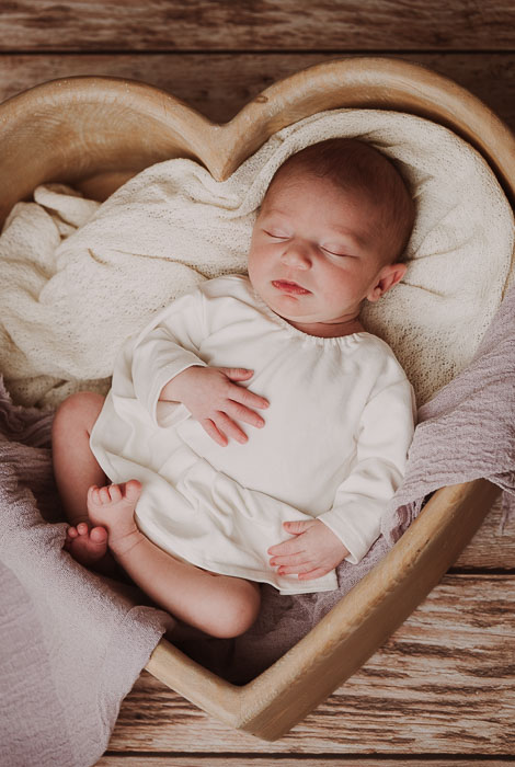 Pasgeboren baby in hart, creme en lila