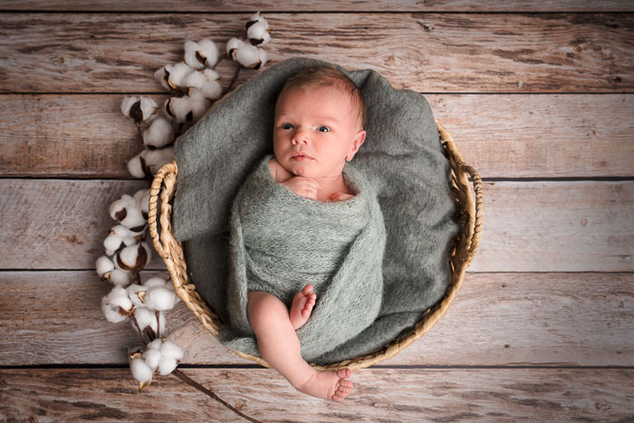 Pasgeboren baby in mandje met groene doek