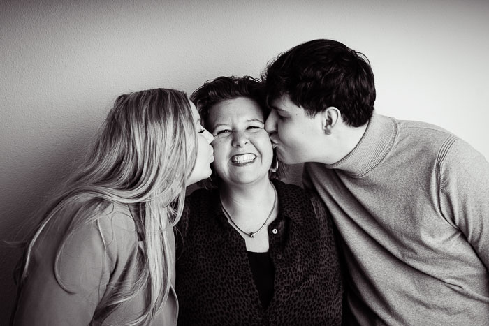 Familie fotoshoot in de studio, kinderen geven mama een kus.