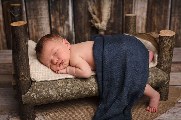 Newbornshoot. Een baby die ligt te slapen op een houten bedje.
