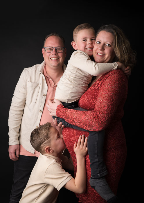 Zwangerschapsshoot van zwangere moeder met gezin bij Studio Suilen. Zwarte achtergrond.