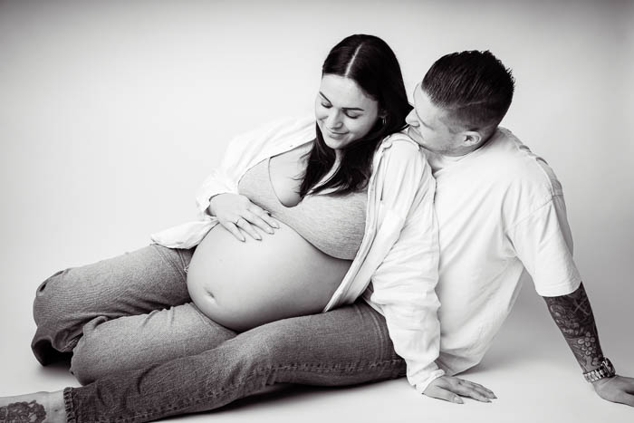Zwangerschapsshoot van koppel in Studio Suilen, voor witte achtergrond. Zwart-wit foto.