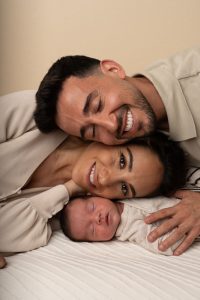 baby met ouders liggend op elkaar met de gezichten.