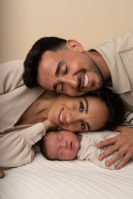 baby met ouders liggend op elkaar met de gezichten.