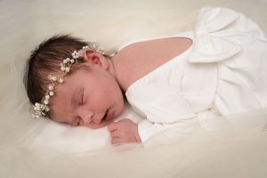 Baby meisje in wit jurkje liggend op een trouwjurk.