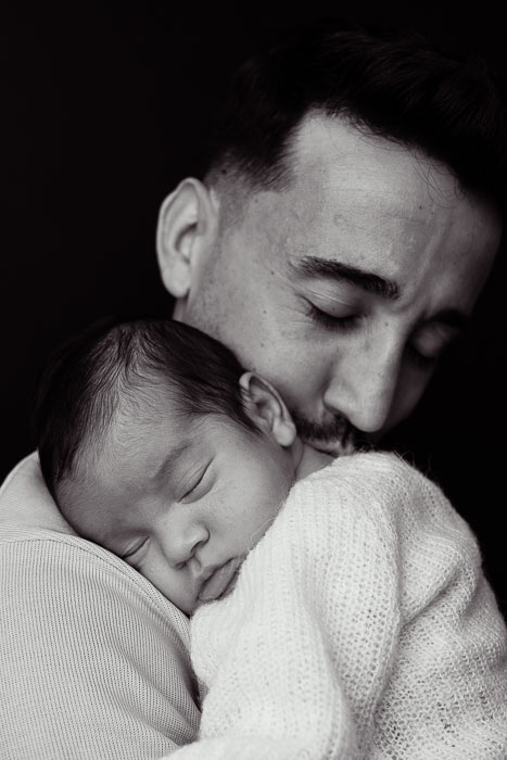 Pasgeboren baby op papa's schouder, zwart-wit.